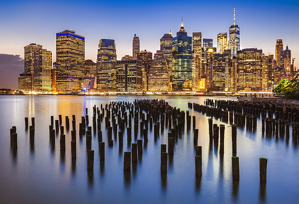 Lower Manhattan skyline, New York skyline, exposed wooden pier stumps, at night, East River, New York, United States of America, North America