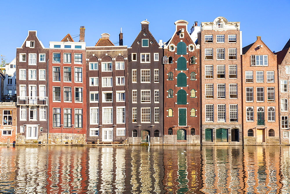 Dutch gables on a row of typical Amsterdam houses with reflections, Damrak Canal, Amsterdam, North Holland, Netherlands, Europe