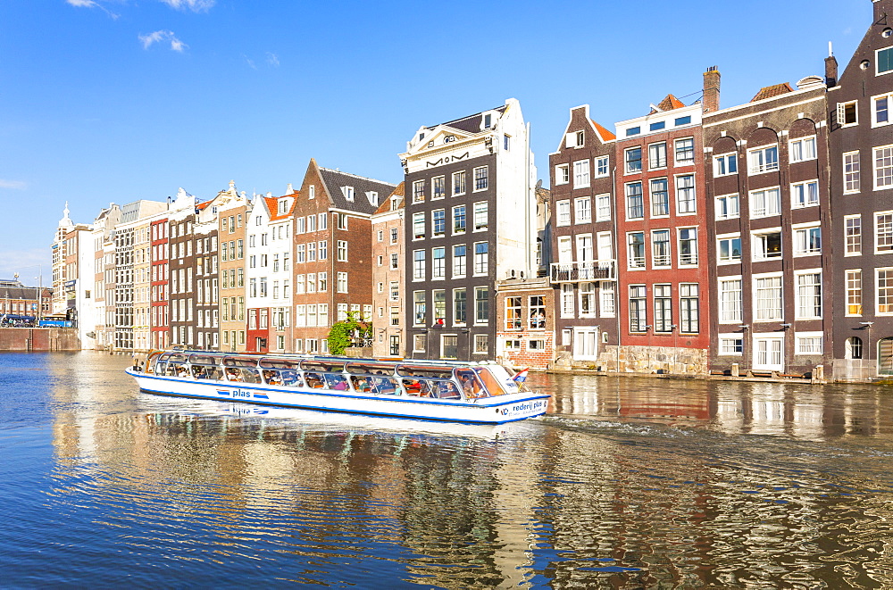 Row of typical Dutch houses on Damrak Canal with canal tour boat, Amsterdam, North Holland, Netherlands, Europe