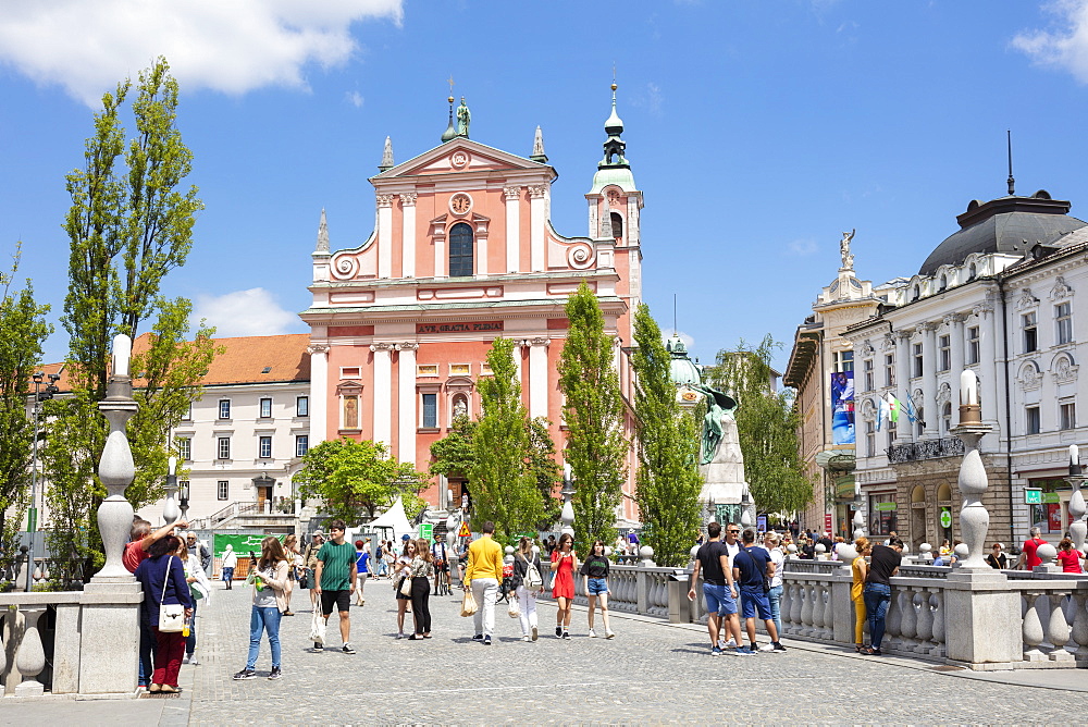 The Pink Franciscan Church in Preseren Square and tourists walking over the Triple Bridge, central Ljubljana, Slovenia, Europe