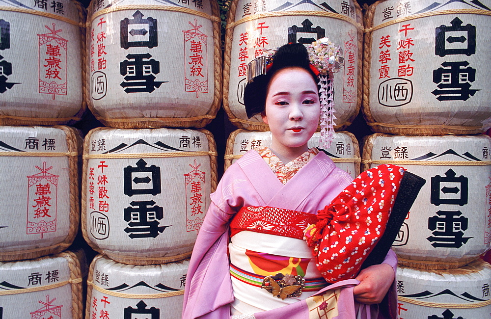 Portrait of a Maiko (a geisha's apprentice) in front of temple lanterns, Kyoto, Japan