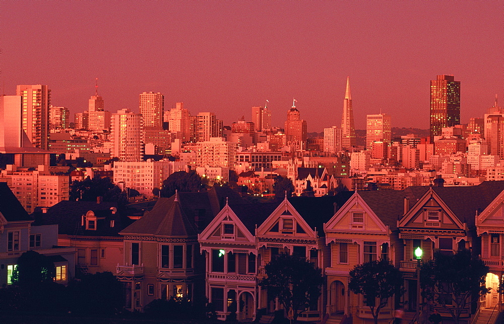 The famous Victorian Painted Ladies of Steiner Street, Alamo Square, with city skyline at dusk, San Francisco, California, USA