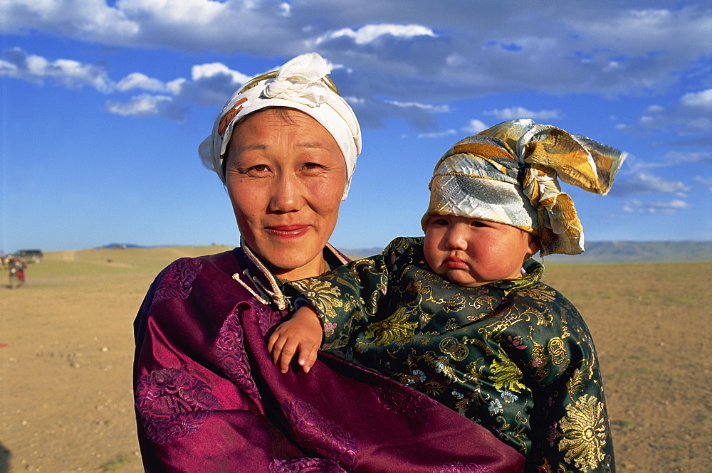 Head and shoulders portrait of a smiling nomad woman and child in traditional clothing, looking at the camera, at Naadam Festival, Altai, Gov-altai, Mongolia, Central Asia, Asia