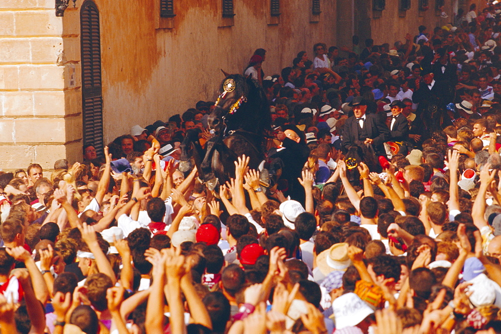 Rider on a rearing horse among the crowds during Sant Joans festival, Ciutadella, Minorca, Spain