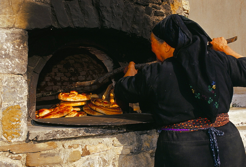 Greek woman baking bread in outdoor communal oven, Olymbos (Olimbos), Karpathos, Dodecanese islands, Mediterranean, Europe