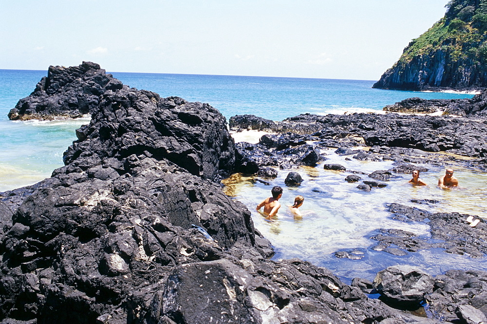 People swimming at Baia dos Porcos inside natural swimming pools, Parque Nacional de Fernando de Norohna, Fernando de Noronha, Pernambuco, Brazil, South America