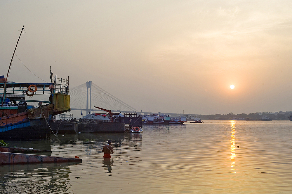 Bather and sunset over the Hooghly River with the Vidyesagar Setu Bridge in the background, Kolkata (Calcutta), West Bengal, India, Asia