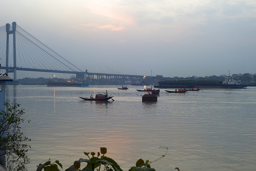 Gondolas rowing along the Hooghly River towards the Vidyasagar Setu Bridge at sunset, Kolkata (Calcutta), West Bengal, India, Asia