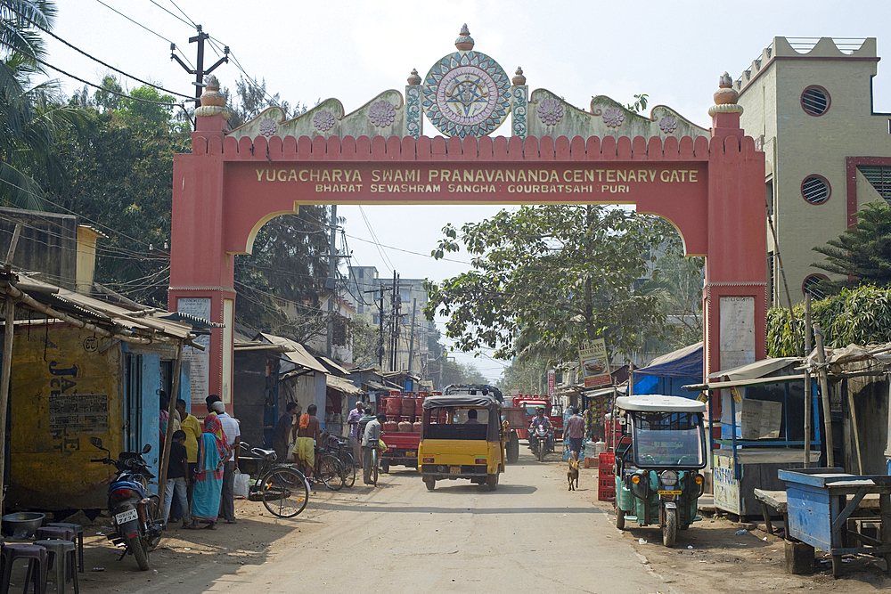 A commemorative archway to the backstreet market quarter with buyers and local traffic, Puri, the oldest of India's four holiest Hindu religious centres, Puri, State of Odisha, India, Asia