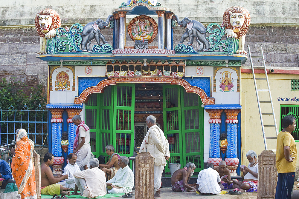 Locals playing cards in front of a small temple in the grounds of the 12th century Jagannath Temple, dedicated to Lord Jagannath, an embodiment of Krishna, Puri, in the State of Odisha, India, Asia