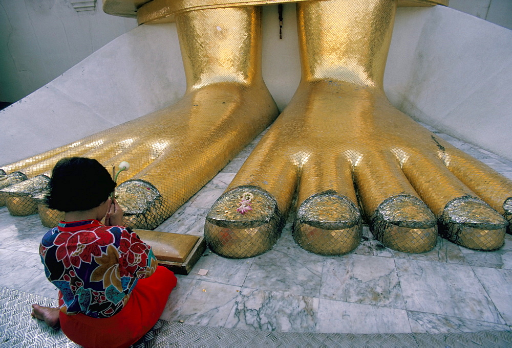 Woman praying at the feet of the Buddha in the temple of the Standing Buddha, Wat Intrawiharn, Bangkok, Thailand, Southeast Asia, Asia