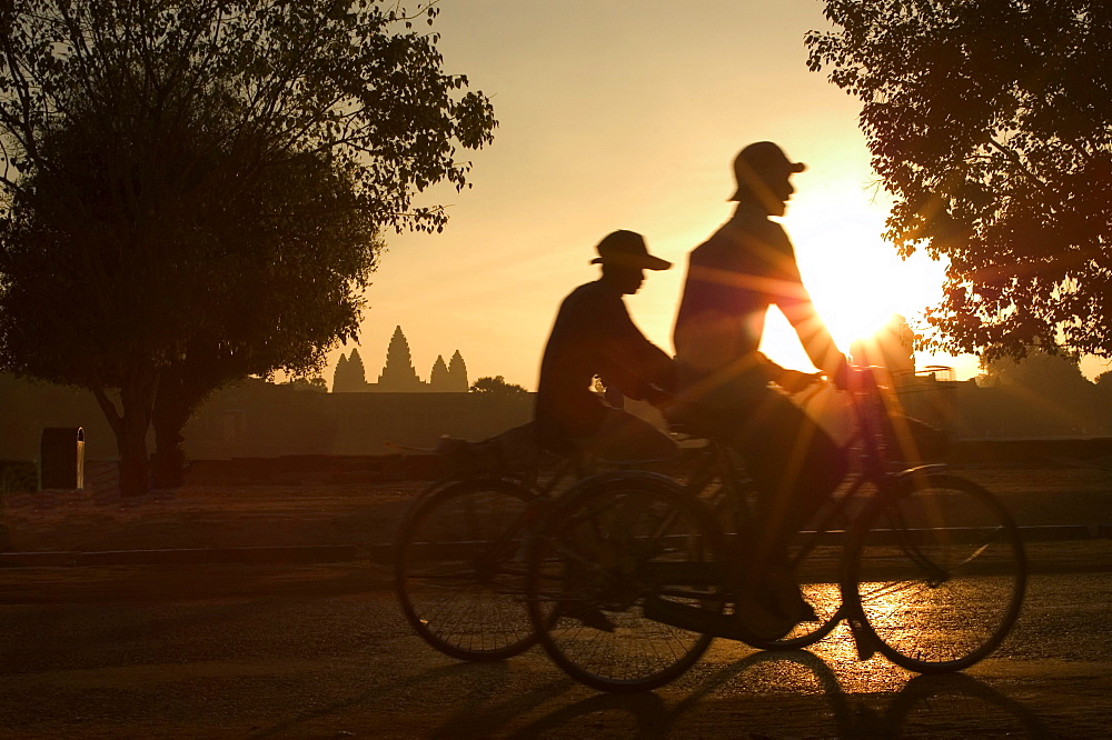 Sunrise, cyclists outside temple complex, Angkor Wat Temple, Cambodia, South East Asia