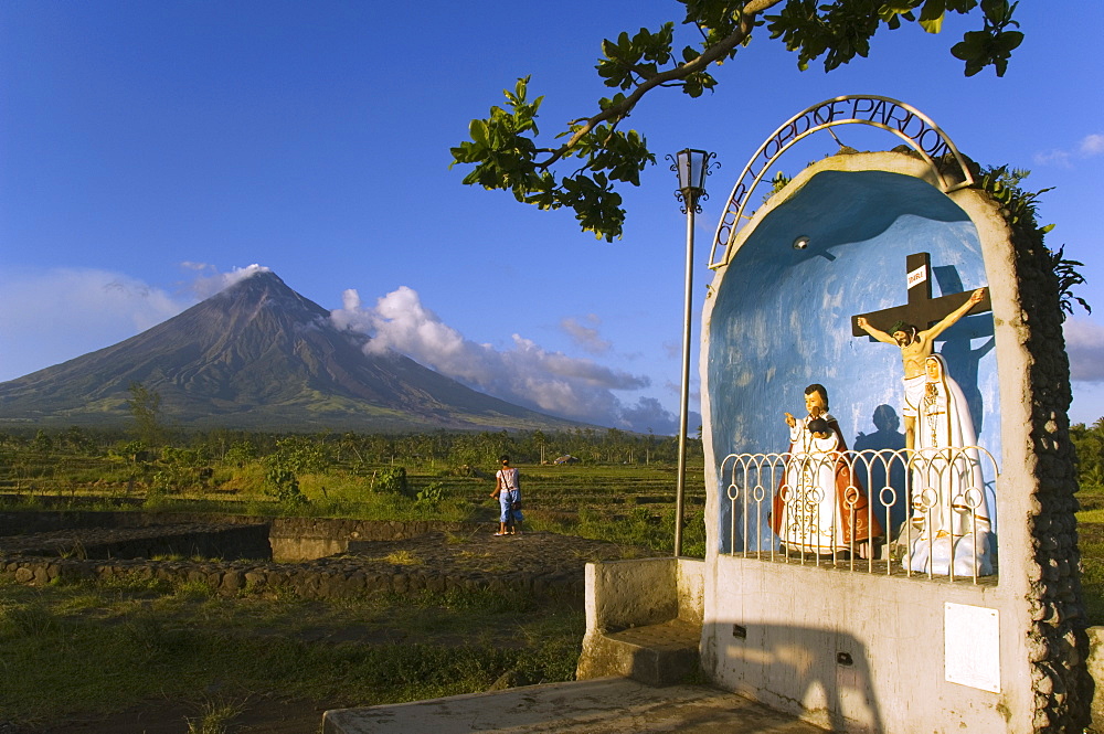 Volcanic cone with plume of smoke of Mount Mayon, 2462m, and grotto or wayside shrine, Bicol Province, Luzon Island, Philippines, Southeast Asia, Asia