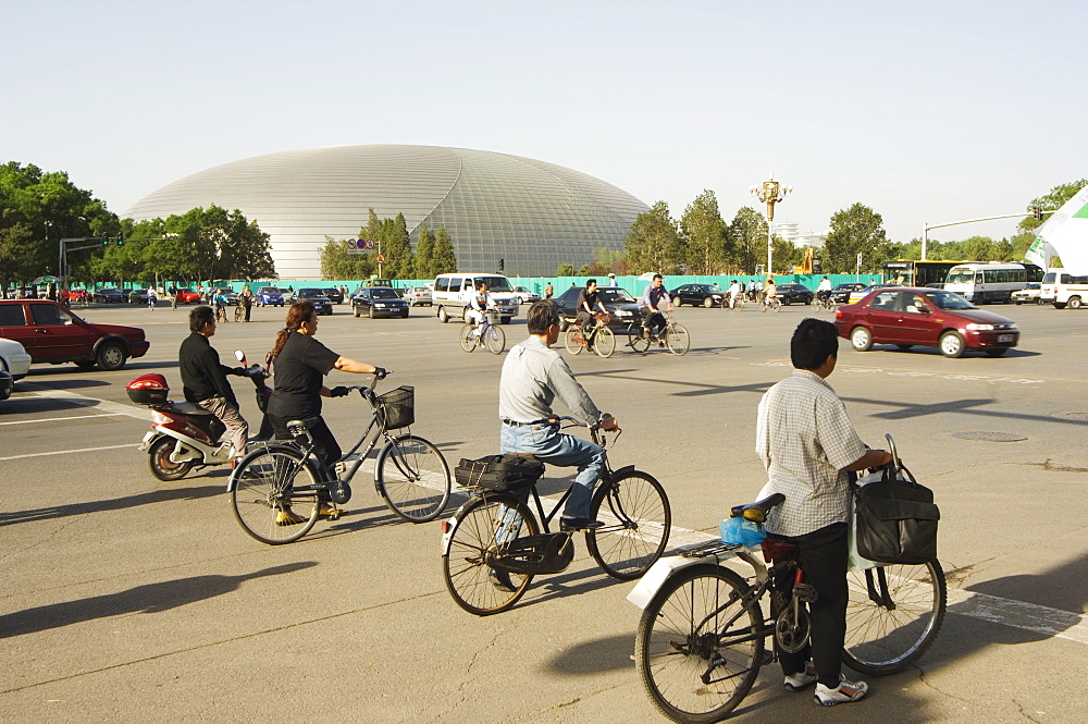 The National Theatre designed by the French architect Paul Andreu, and cyclists commuting in central Beijing, Beijing, China, Asia