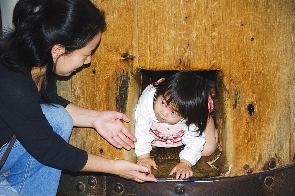 Child crawling though hole in wooden column to reach Nirvana, Todaiji (Big Buddha) Temple, constructed in the 8th century, Nara City, Nara Prefecture, Honshu Island, Japan, Asia