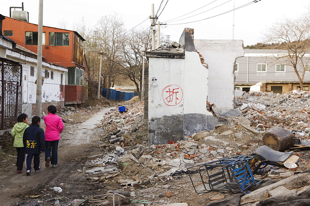 Girls walking in a neighbourhood Hutong partially destroyed and marked for demolition, Beijing, China, Asia