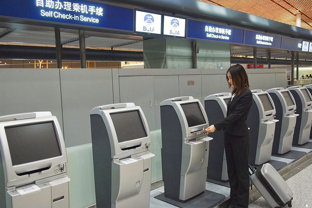 A Chinese business woman using the self service check in machines at Beijing Capital Airport part of new Terminal 3 building opened February 2008, second largest building in the world, Beijing, China, Asia