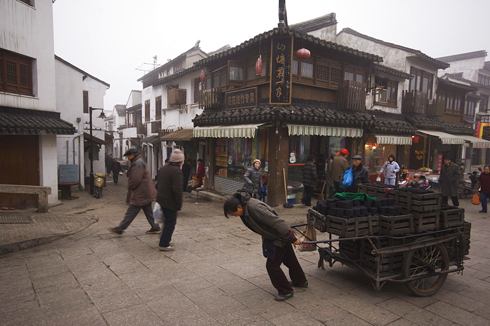 A woman pulling a cart of charcoal bricks on an old street in Shantang district of Suzhou, Jiangsu Province, China, Asia 