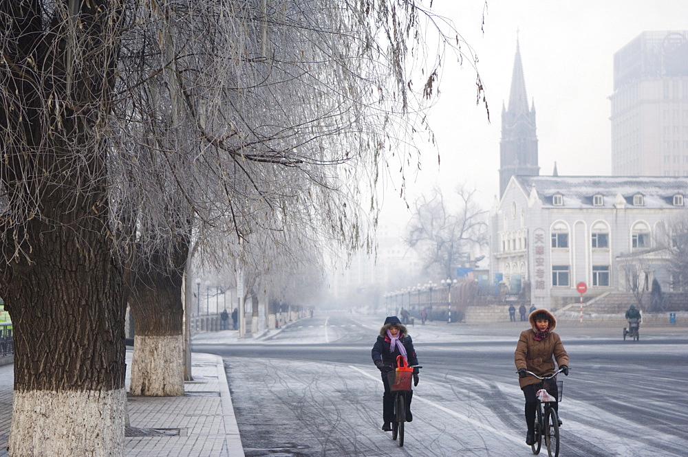 Cyclists in a winter wonderland and Catholic church in Jilin City, Jilin Province, Northeast China, China, Asia