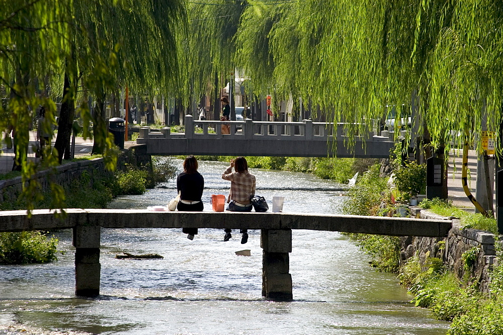 Two girls sitting on bridge, Kyoto city, Honshu, Japan, Asia