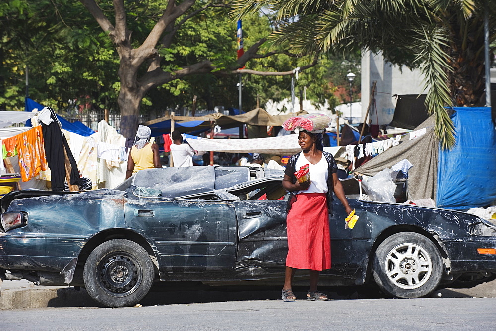 Woman in front of a damaged car, January 2010 earthquake, downtown, Port au Prince, Haiti, West Indies, Caribbean, Central America