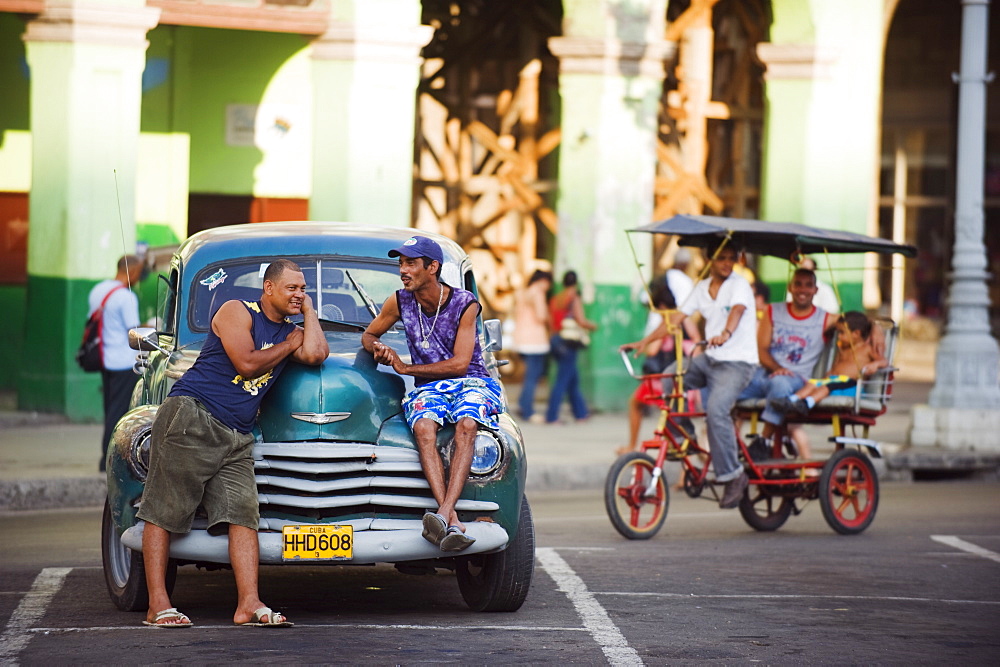 Men relaxing on a 1950s classic American car, Central Havana, Cuba, West Indies, Caribbean, Central America