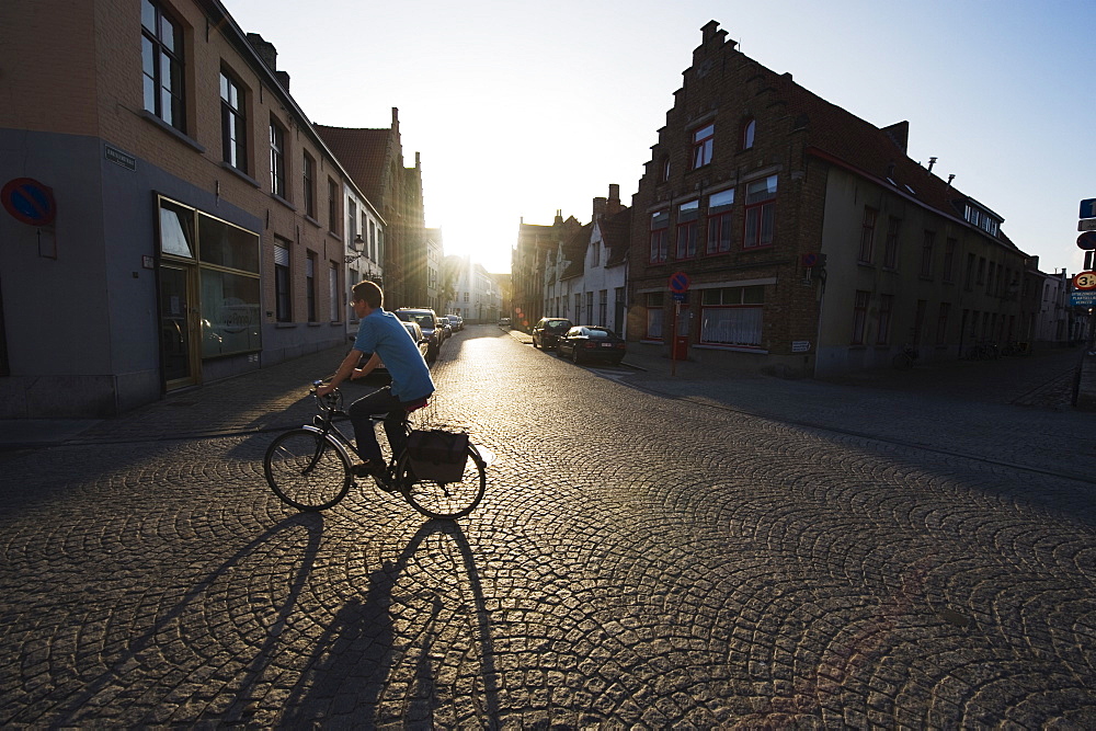 Sunset and shadow of a cyclist on cobbled street, old town, UNESCO World Heritage Site, Bruges, Flanders, Belgium, Europe