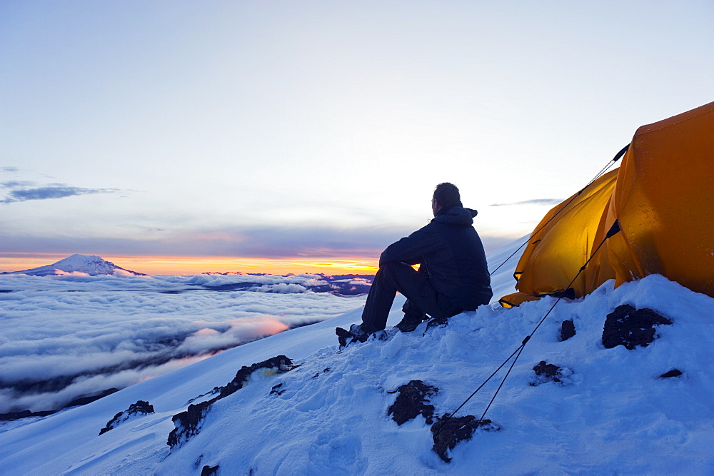 Climber looking at sunrise on Volcan Cotopaxi, 5897m, highest active volcano in the world, Ecuador, South America