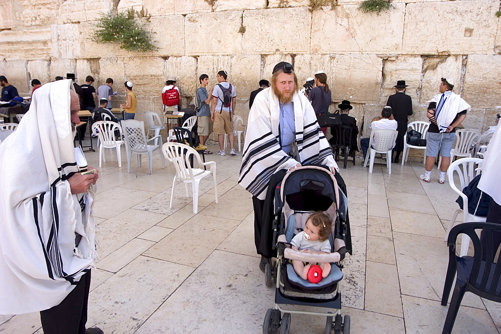 Jewish man with child in pram, praying at the Western Wailing Wall, Old Walled City, Jerusalem, Israel, Middle East