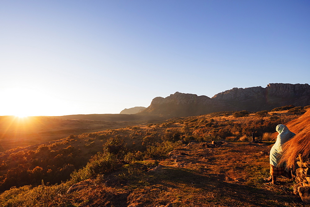 A local man warming up in the morning sun, Andringitra National Park, Ambalavao, central area, Madagascar, Africa