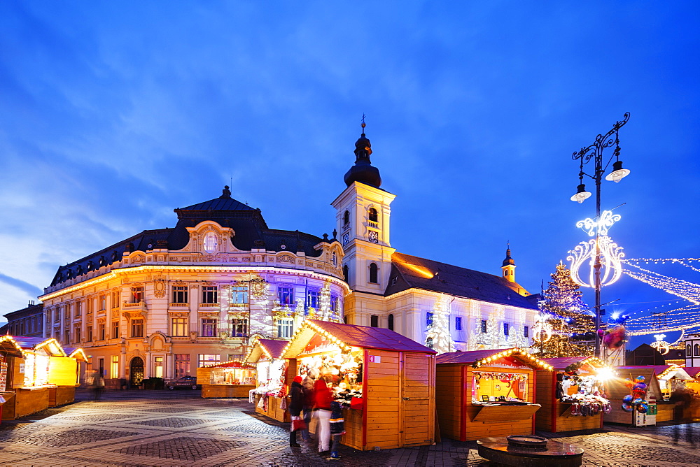 Christmas market in Plaza Piata Mare, City Hall and Baroque Jesuit Church, Sibiu, Romania, Europe