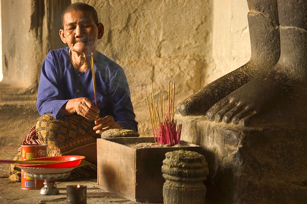 Pilgrim making an offereing at Angkor Wat Temple, feet of statue, Cambodia, Southeast Asia, Asia