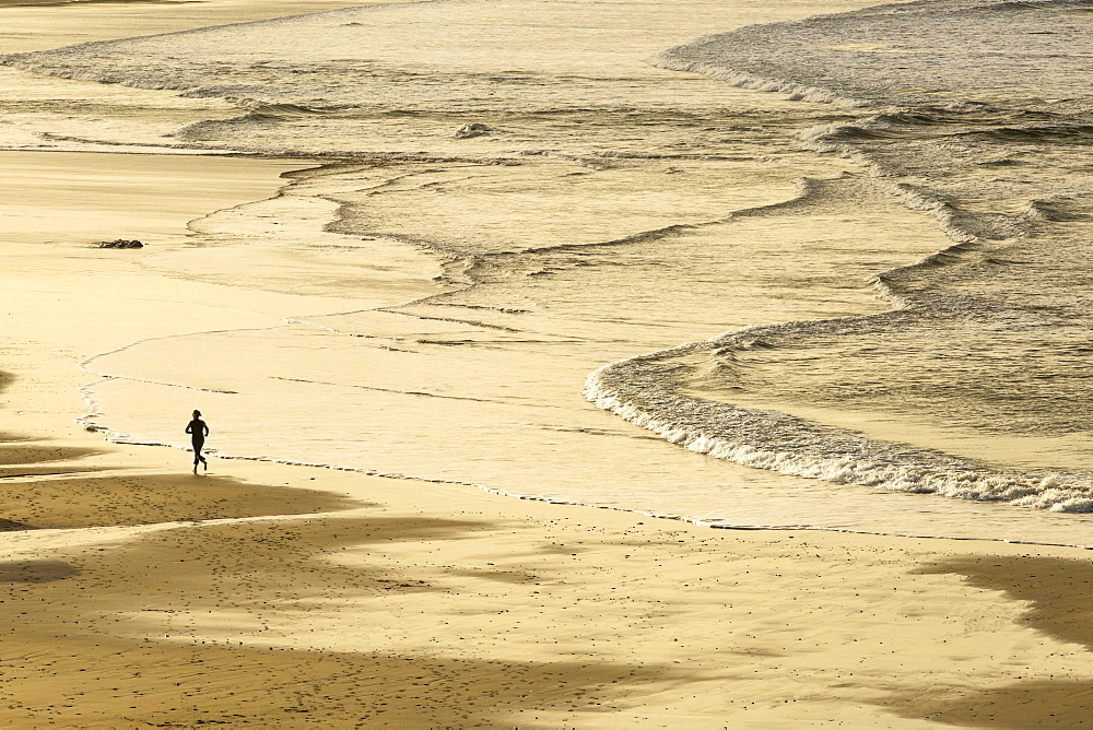 Woman jogging at sunrise on Gwithian Beach, Cornwall, England, United Kingdom, Europe