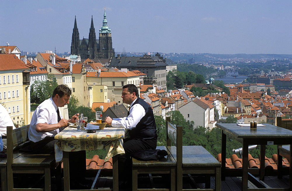 Two men having lunch outdoors while enjoying the view of Prague Castle from the Restaurant Ozivle drevo, Hradcany, Prague, Czech Republic, Europe