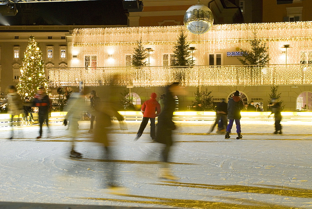 Ice skating at night on ice rink at Mozartplatz square, Salzburg, Austria, Europe