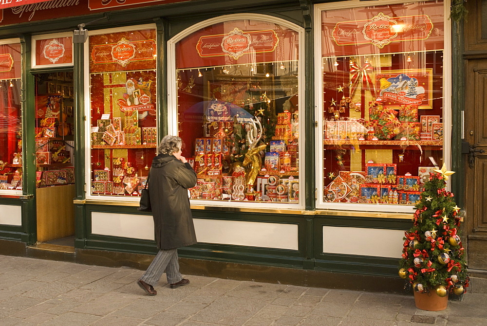 Woman looking at chocolate shop selling Mozart chocolates and other Christmas sweets, Altermarkt Square, Salzburg, Austria, Europe