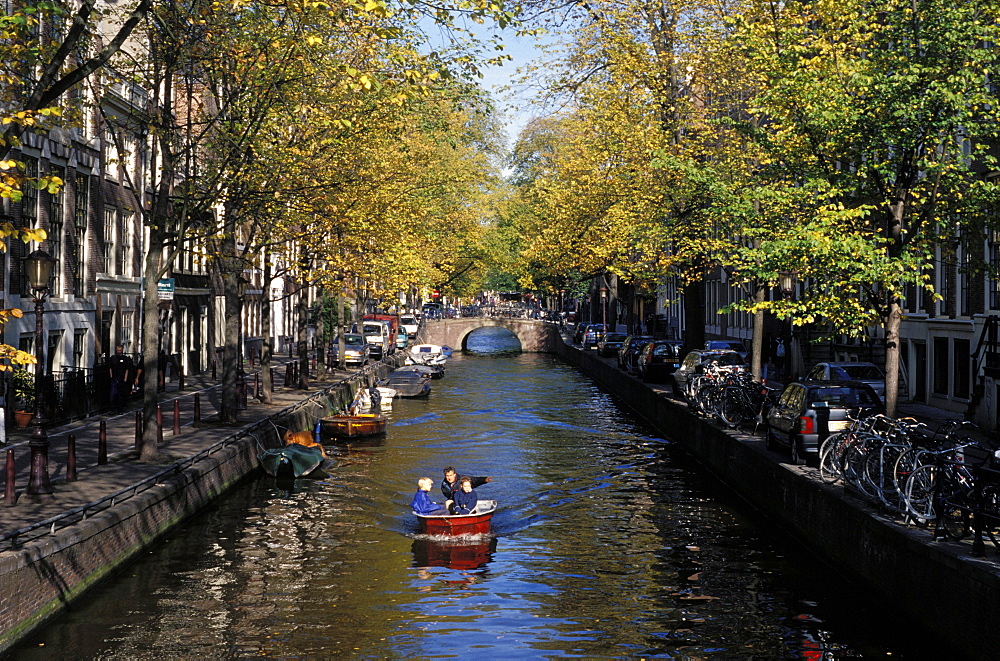 Small boat on tree-lined Oudezijds Achtenburg Wal canal in the autumn, Amsterdam, The Netherlands (Holland), Europe