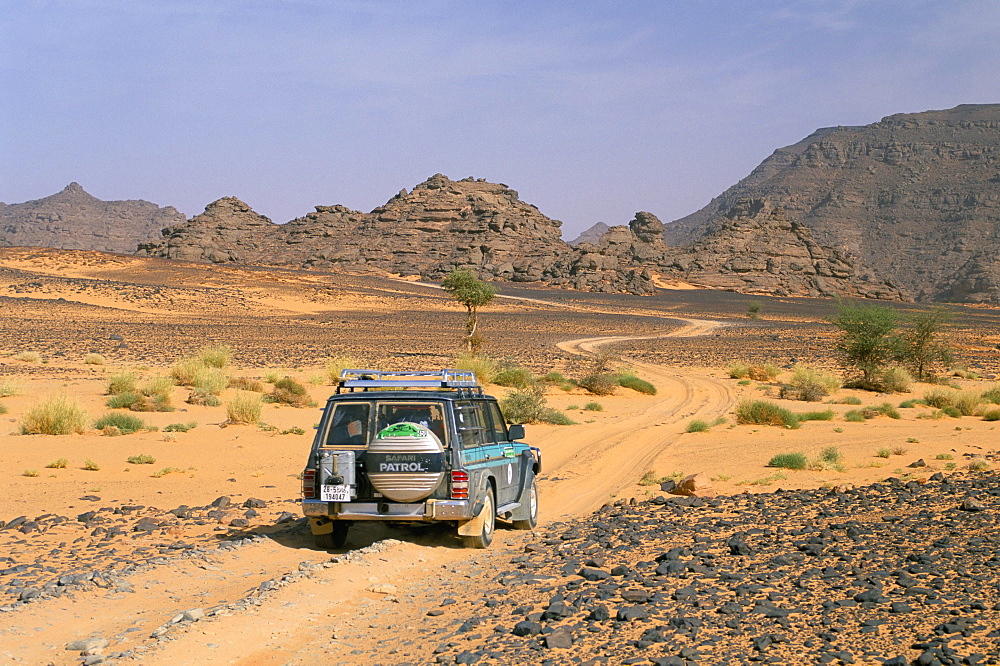 Jeep driving on desert road, Akakus, Sahara desert, Fezzan, Libya, North Africa, Africa