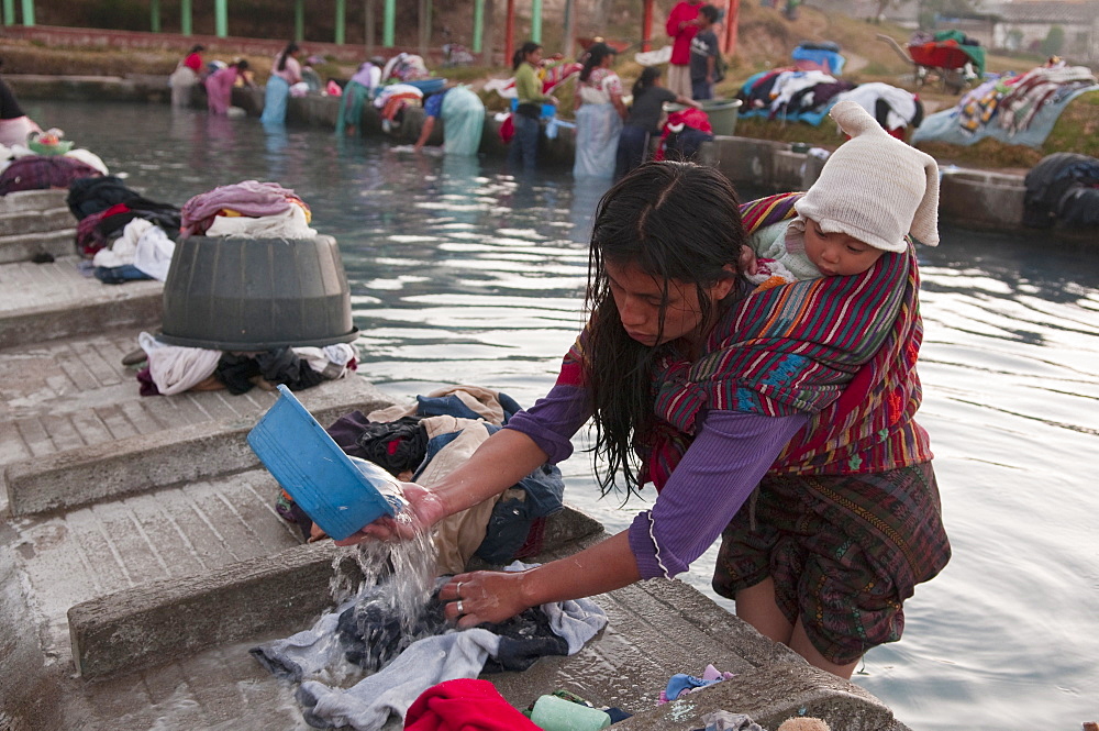 Woman with baby washing clothes at public laundry, Totonicapan, Guatemala, Central America