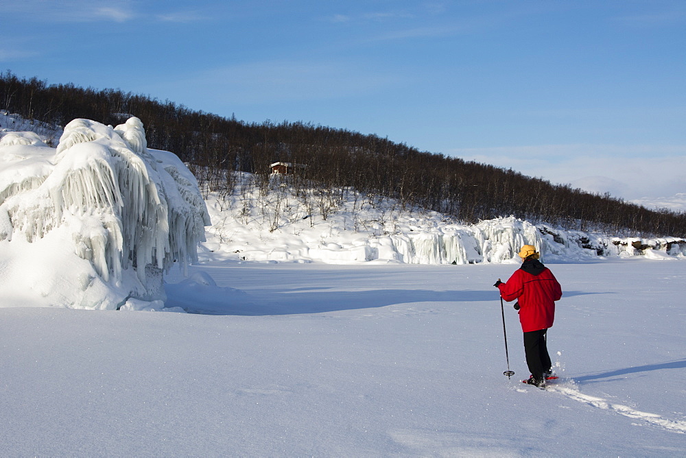 A woman walking across frozen Tornetrask Lake, Abisko National Park, Sweden, Scandinavia, Europe