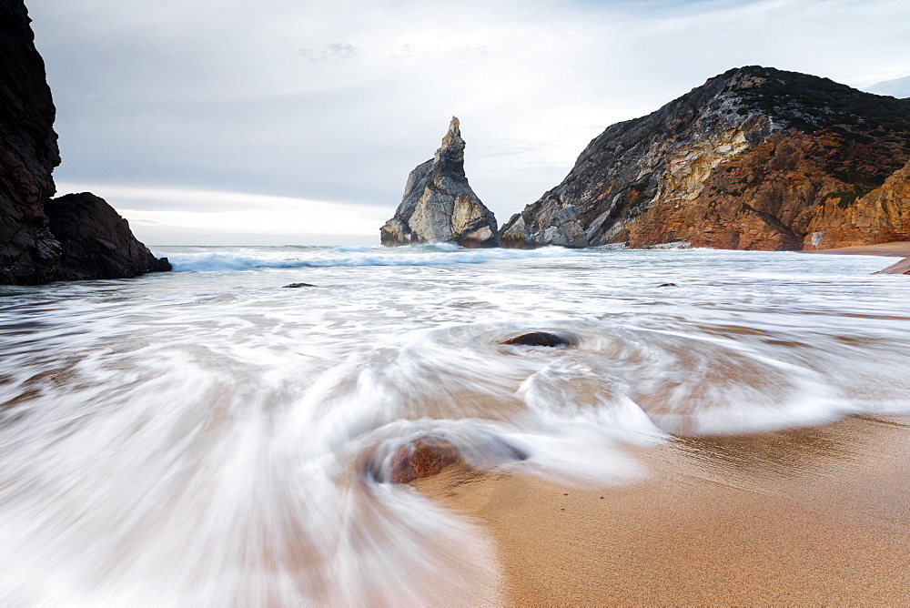 Ocean waves crashing on the sandy beach of Praia da Ursa surrounded by cliffs, Cabo da Roca, Colares, Sintra, Portugal, Europe