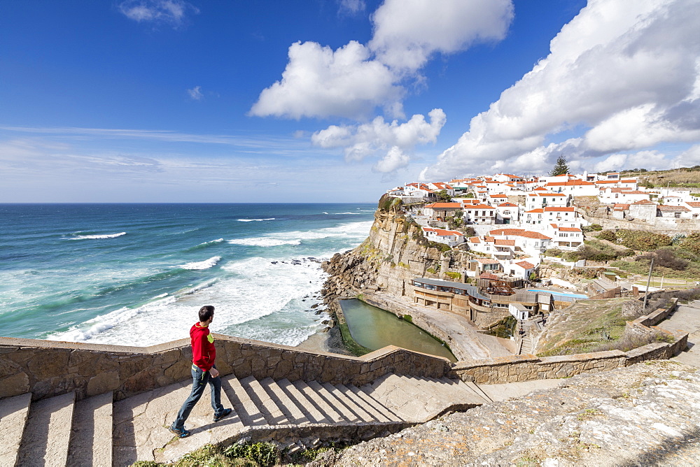 Tourist admires the perched village of Azenhas do Mar surrounded by the blue water of the Atlantic Ocean, Sintra, Portugal, Europe