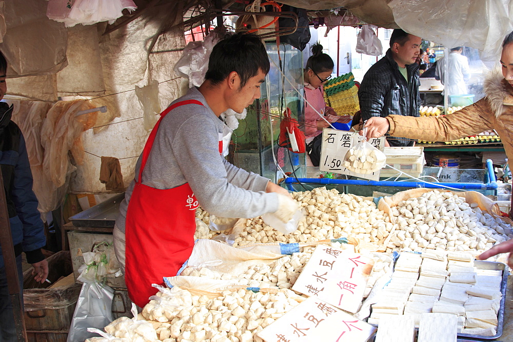 Man selling different varieties of tofu in a market in Kunming, China