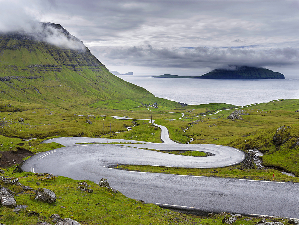 Mountain road to the  Nordradalur at the west coast. Koltur island in the background.  The island Streymoy, one of the two large islands of the Faroe Islands  in the North Atlantic.  Europe, Northern Europe, Denmark, Faroe Islands