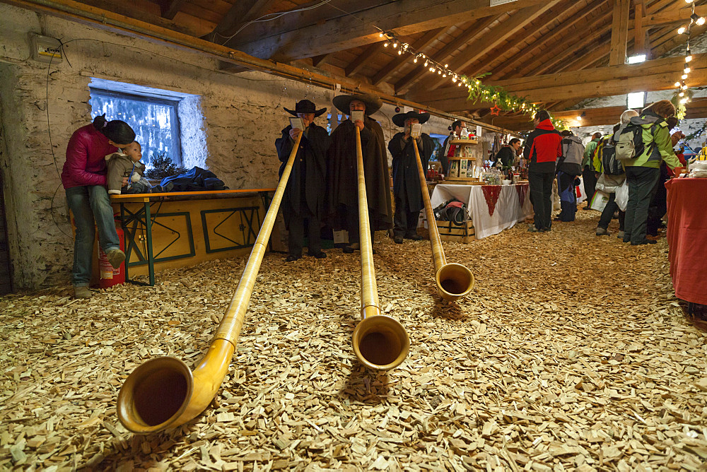 Musicans in traditional garment playing the Alphorn or Alpenhorn on a Christmas Market in Martell Valley (Martello). Europe, Central Europe, Italy, South Tyrol, December