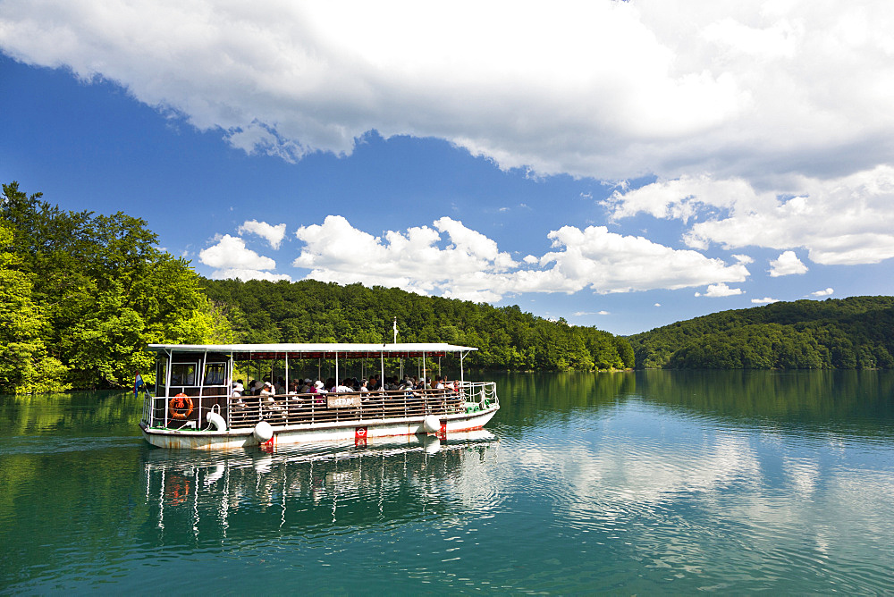 The Plitvice Lakes in the National Park Plitvicka Jezera in Croatia. Visitors taking a cruise on lake Kozjak.  The Plitvice Lakes are a string of lakes connected by waterfalls. They are in a valley, which becomes a canyon in the lower parts of the National Park. The waterfalls are formed mostly by travertine (tufa) barriers between the lakes. The lakes are listed as  UNESCO World heritage and are visited by close to one million tourists per year. Europe, South Eastern Europe, Croatia