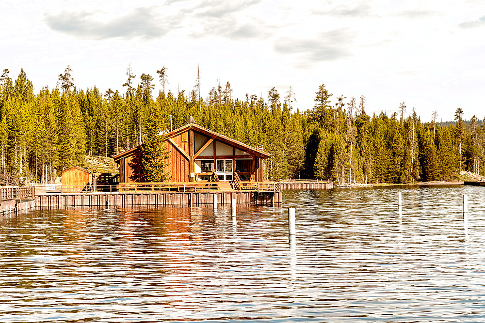 Wooden homr on Yellowstone Lake with trees water reflections.