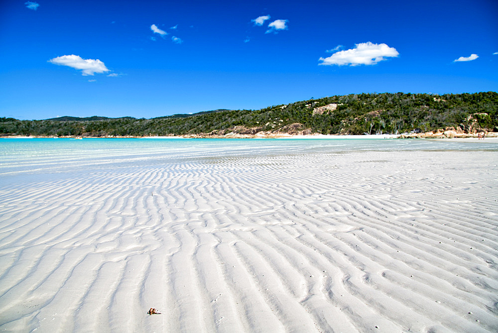 Crystal clear water on a wonderful beach. Shallow ocean water with island view.