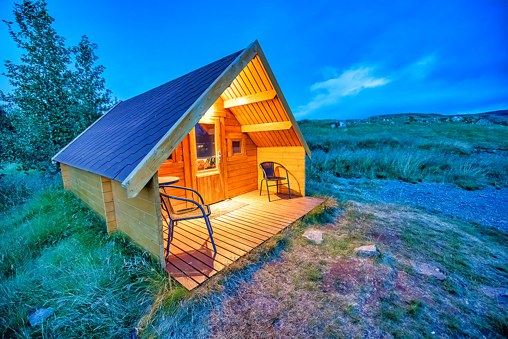 Beautiful chalet isolated in the mountains at sunset. Wooden front with chairs