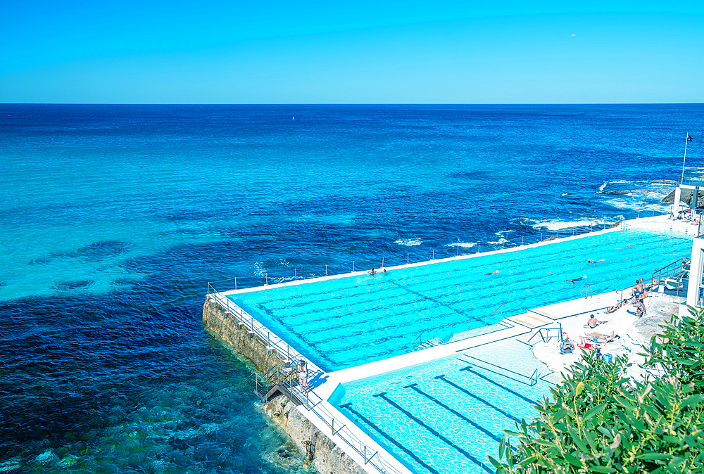 Swimmers enjoy beautiful pool along the sea.